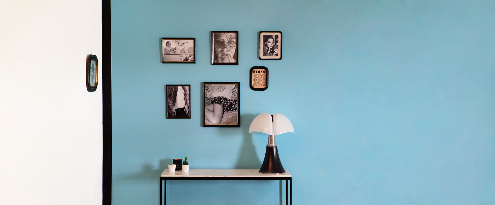 Disposition de cadres photos vintages, au dessus d'une table, sur un mur bleu